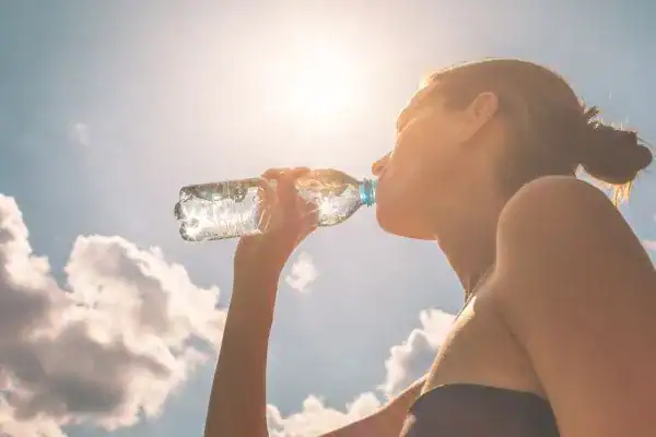 Image of woman drinking water to hydrate Walton-on-Thames after run.