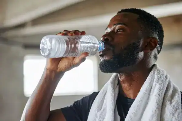 Image of man drinking water to improve hydration Walton-on-Thames after work out.